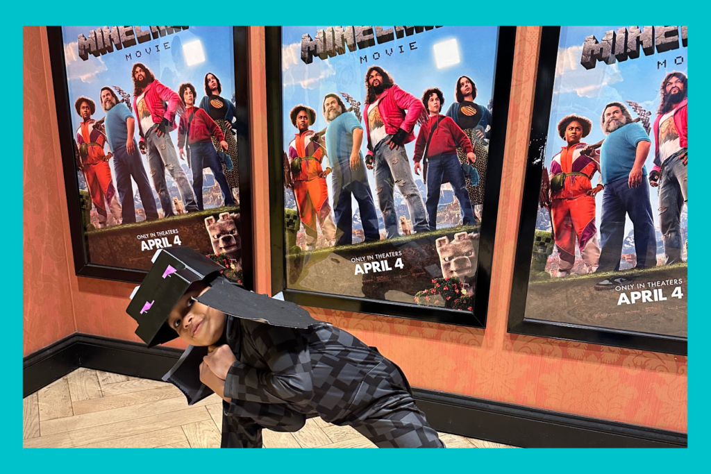Jack posing in front of the Minecraft movie poster in a costume