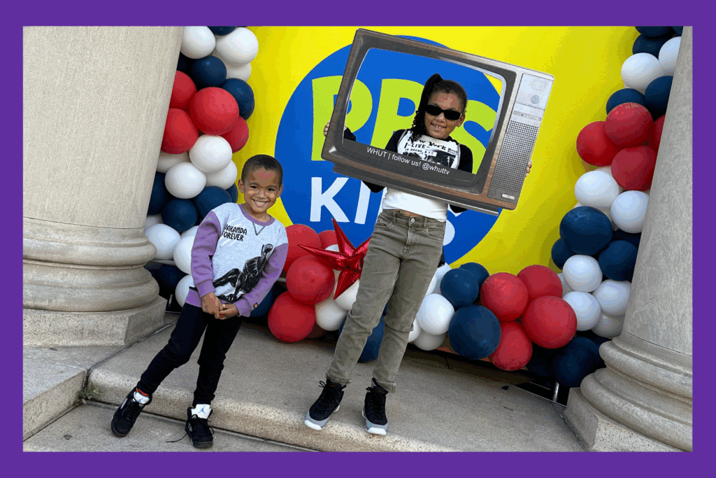 Liv and Jack pose at Howard Homecoming in front of the PBS KIDS sign