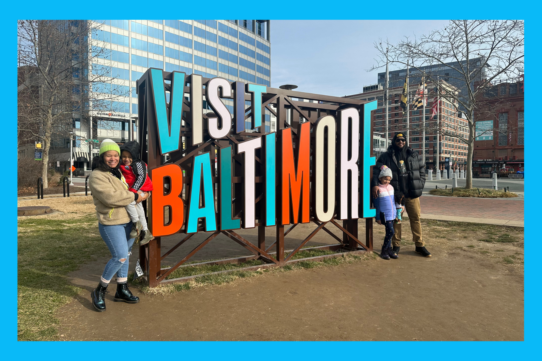 The Acors standing in front of the Visit Baltimore sign