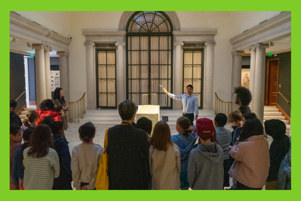 a class of students listen to a representative at a museum