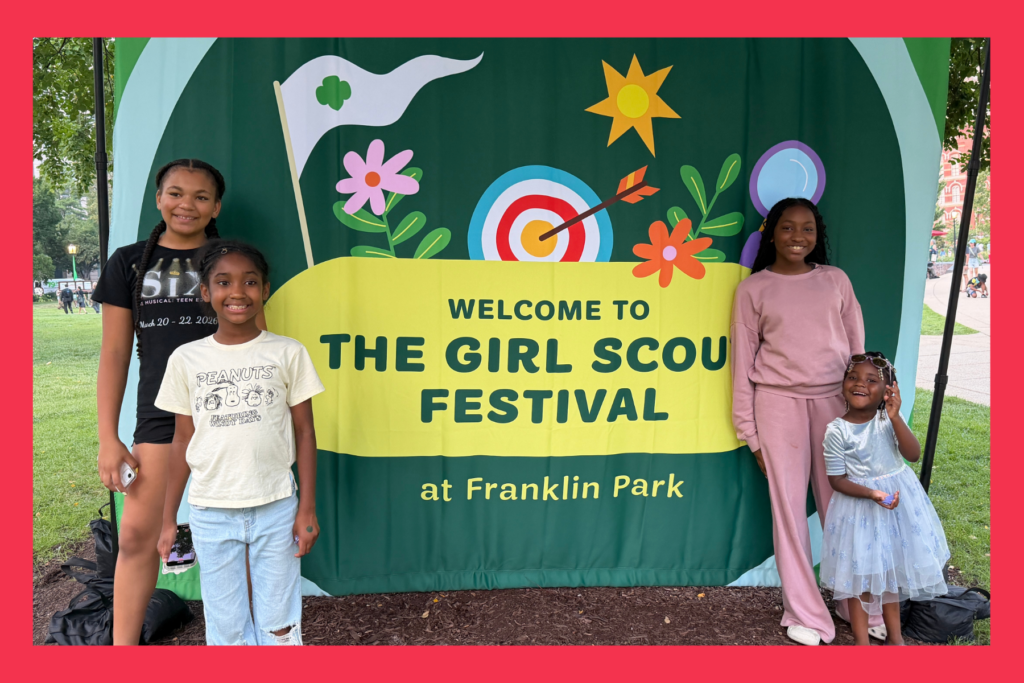 4 young girls pose with the Welcome to the Girls Scout Festival at Franklin Park banner.