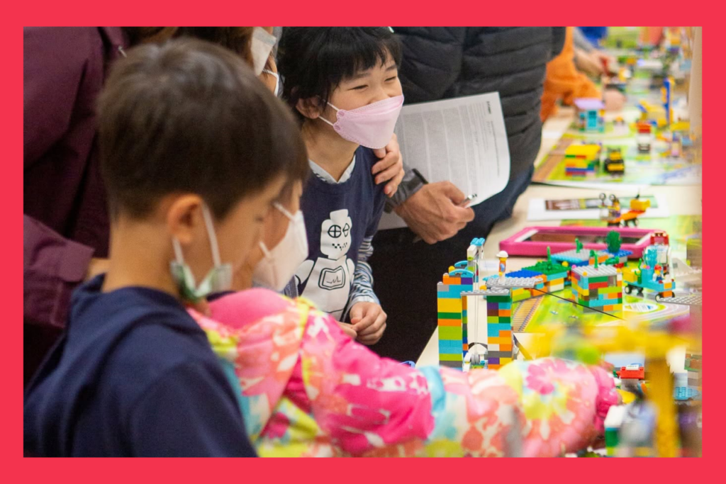 kids with masks on play with LEGOS at the robotics day celebration