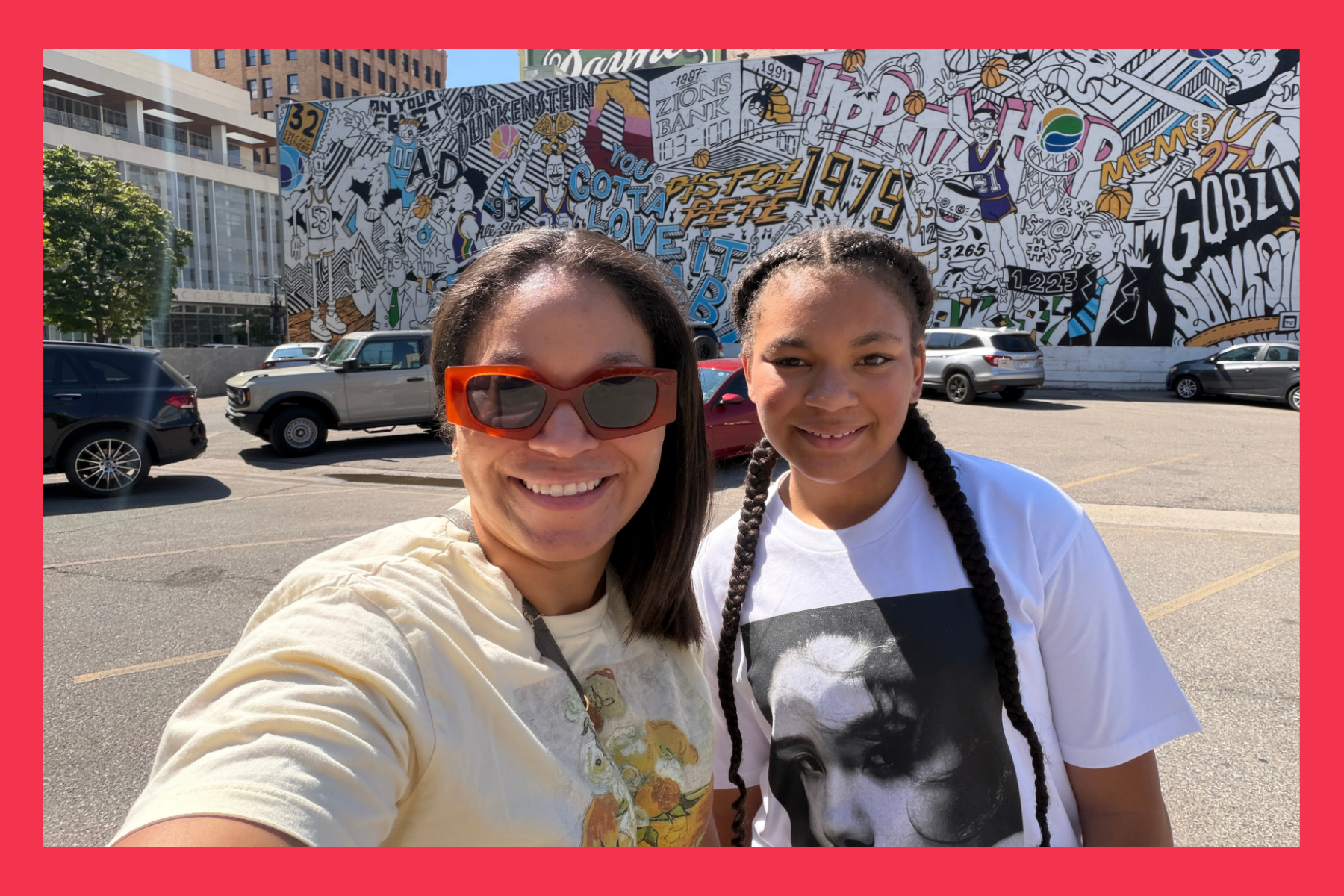 mom and daughter smile in front of a billboard.