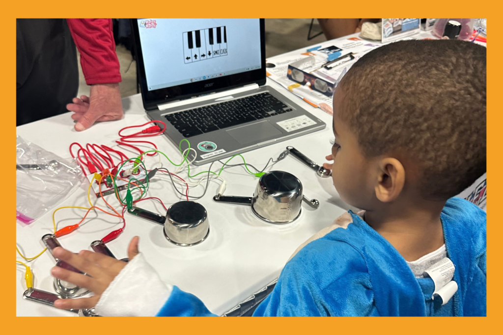 a boy in a costume creates music through circuits at a festival.