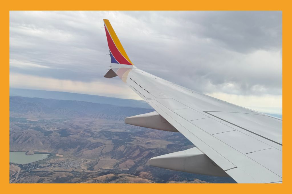 airplane wing midair over mountainous terrain.