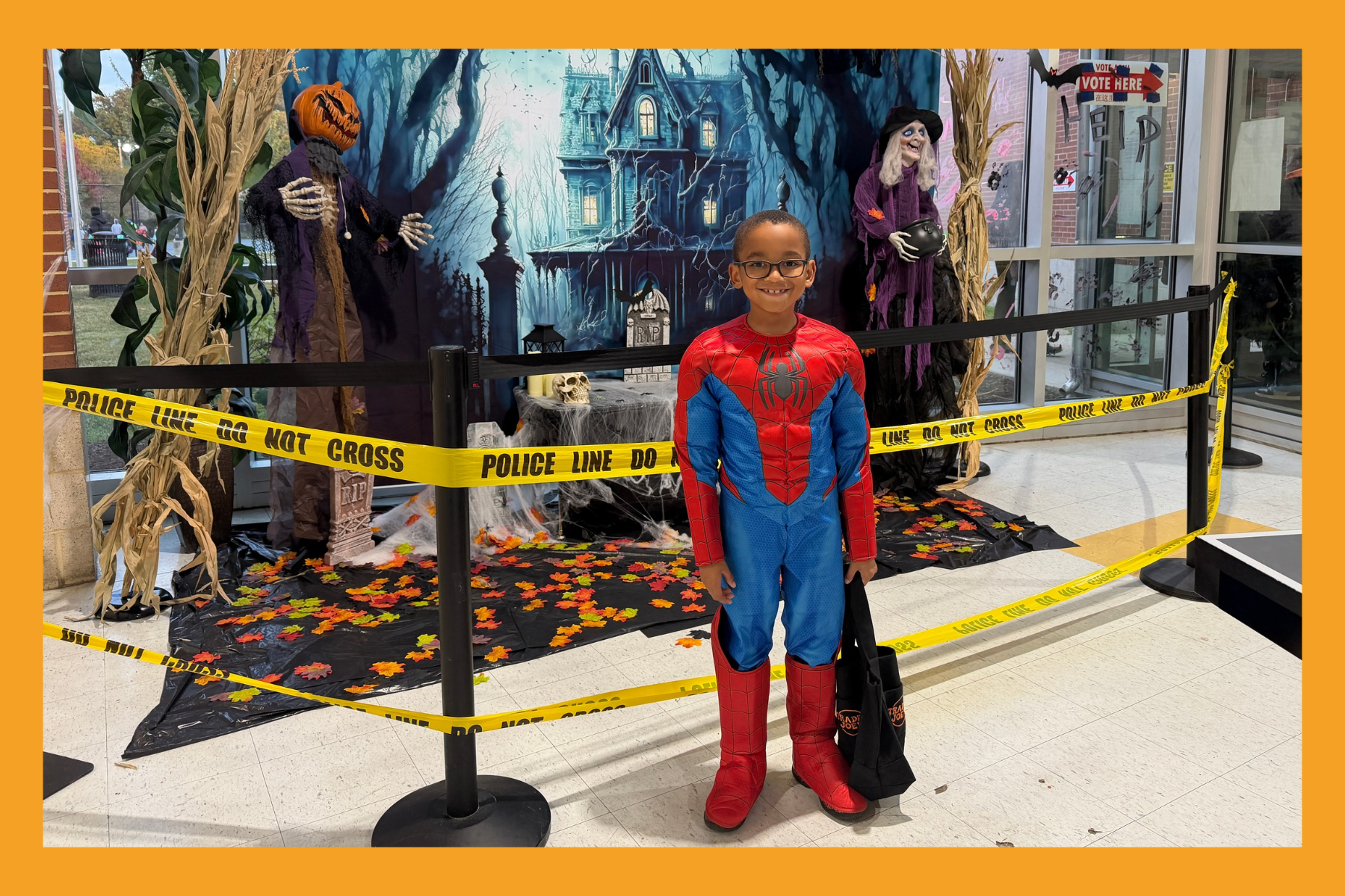 a young boy in a Spiderman costume stands in front of a scary scene at at a recreation center.
