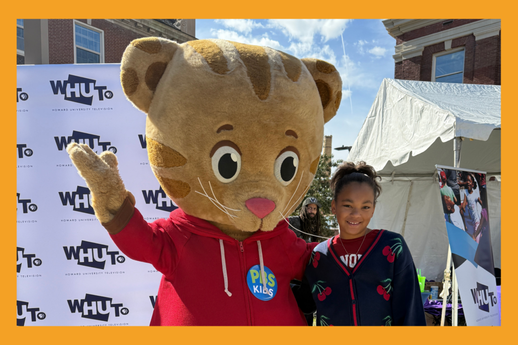 PBS Kids character Daniel tiger poses with a young girl at Howard homecoming.