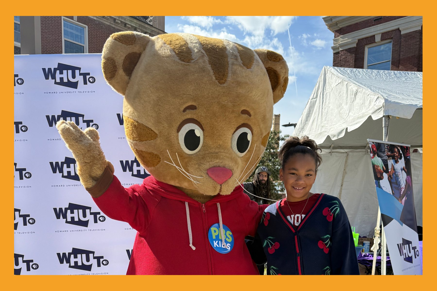 PBS Kids character Daniel tiger poses with a young girl at Howard homecoming.