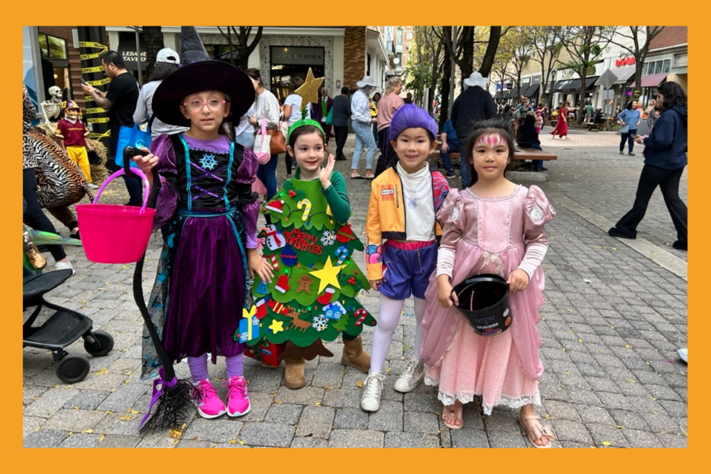 four young girls in halloween costumes at an outdoor festival.